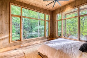 A bedroom with large windows, wooden walls, and a bed. - Greenridge - Hot tub & mountain views (Blue Ridge Mountains)