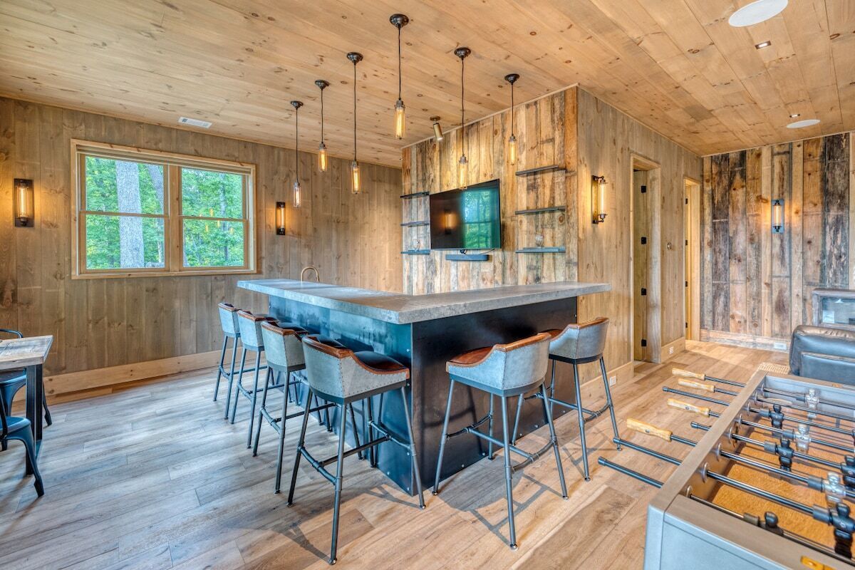 A wooden interior with a bar area, seating, and a foosball table.