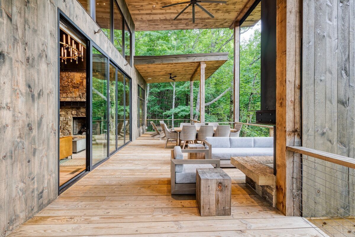 Una terraza de madera con mobiliario exterior y una chimenea de piedra.
