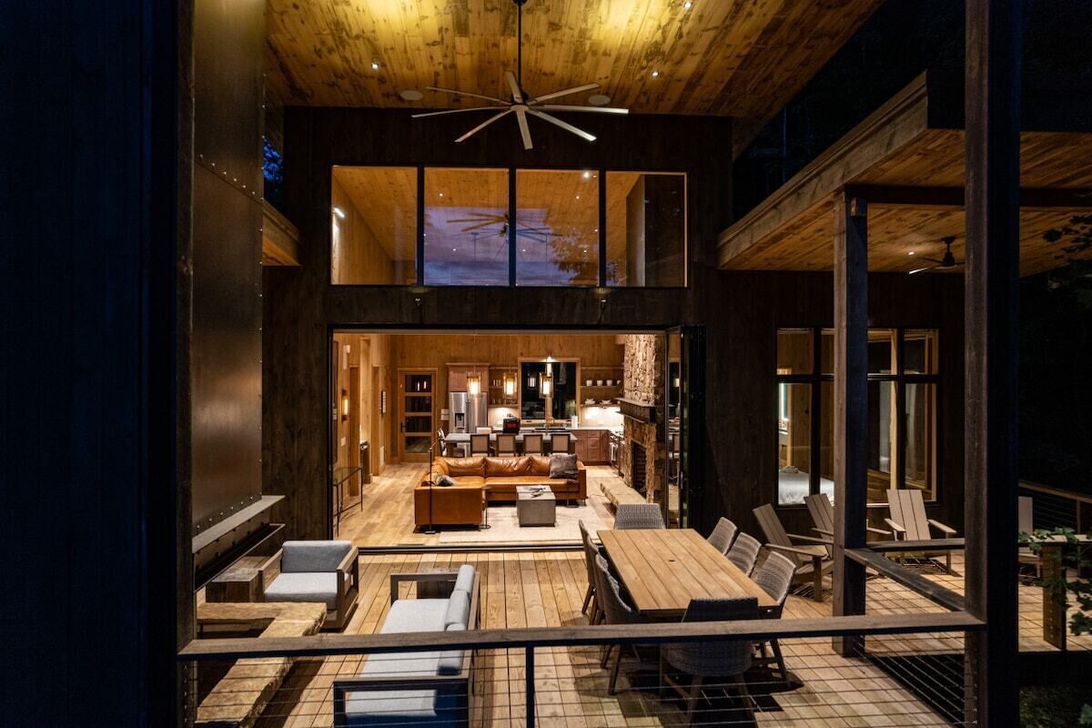 A modern interior with a dining area, seating, and a kitchen visible through a large window.
