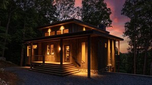 A wooden cabin with a porch, steps leading to the entrance, and a view of the surrounding forest. - Greenridge - Hot tub & mountain views (Blue Ridge Mountains)