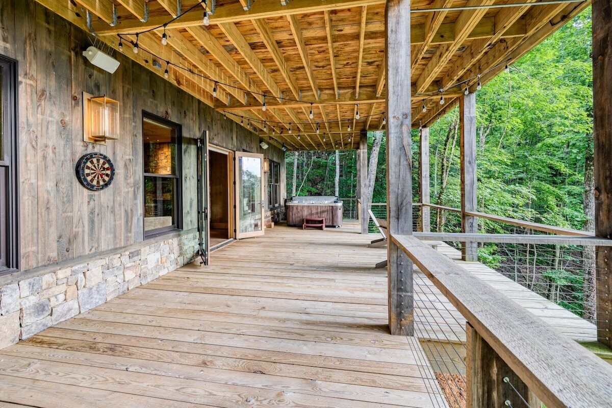 A wooden deck with a covered area, stone base, and a dartboard.