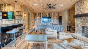 A room with a wooden ceiling, a ceiling fan, a foosball table, a television, and a stone fireplace. - Greenridge - Hot tub & mountain views (Blue Ridge Mountains)