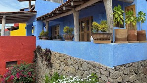 Un bâtiment bleu avec un toit en tuiles, des poutres en bois et des plantes en pot.