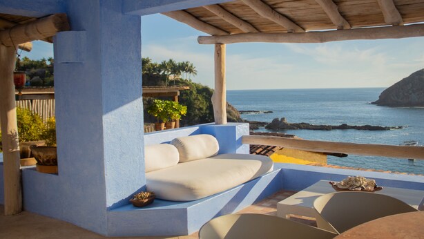 Une terrasse avec vue sur la mer, comprenant un espace salon avec des coussins et une table.