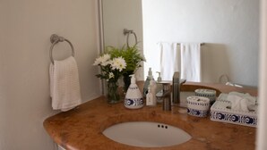 Une salle de bain avec un lavabo rond, des serviettes blanches, un vase avec des fleurs et divers produits de toilette.