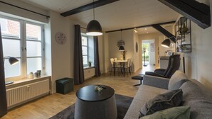 A modern living room with a sofa, a round coffee table, and a dining area with a table and chairs. - Guesthouse (Sønderborg)