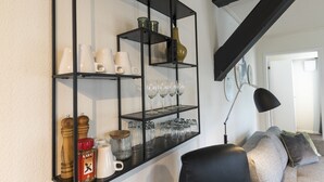 A living room with a black metal shelving unit displaying various glassware and jars. - Guesthouse (Sønderborg)