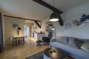 A modern living room with a grey sofa, a round coffee table, and a dining area with a table and chairs. - Guesthouse (Sønderborg)
