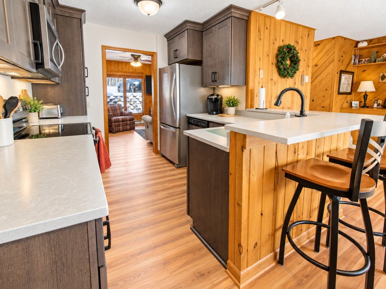 Une cuisine moderne avec des meubles en bois, des appareils électroménagers en acier inoxydable et un îlot central doté de tabourets de bar.