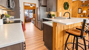 Une cuisine moderne avec des meubles en bois, des appareils électroménagers en acier inoxydable et un îlot central doté de tabourets de bar.