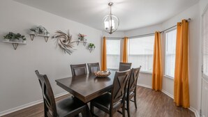 Une salle à manger avec une table et des chaises en bois, entourée de murs blancs et dotée d’un plancher en bois.