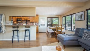 A modern kitchen with wooden cabinets, a bar area, and a dining space with a table and chairs. - Gorgeous Gem in West Sedona (Sedona)