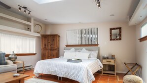 A bedroom with a large bed, a wooden cabinet, a bedside table, a mirror, and a window with blinds. - Gorgeous Gem in West Sedona (Sedona)