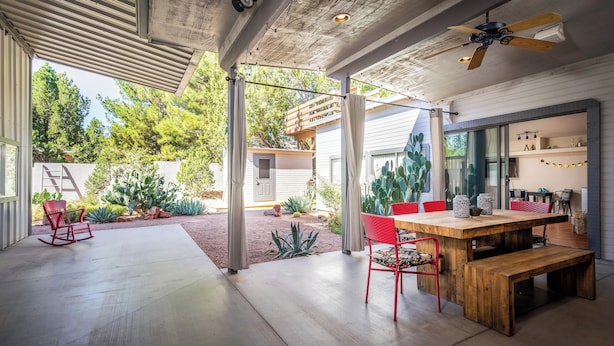 A spacious patio with a wooden table and chairs, a ceiling fan, and a view of a garden with various plants. - Gorgeous Gem in West Sedona (Sedona)