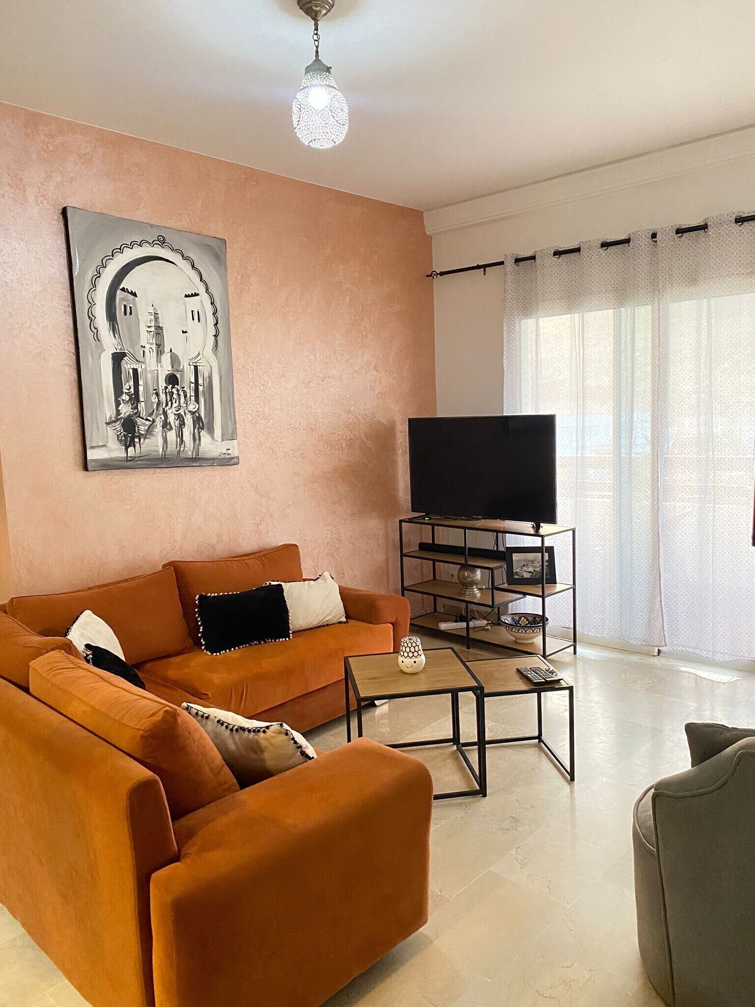 Ein Wohnzimmer mit Sofa, Couchtisch, TV-Möbel und einem Bild an der Wand.