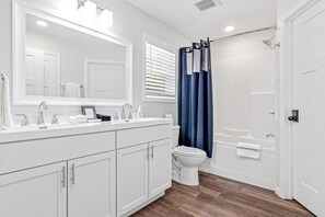 Un bagno moderno con un mobile lavabo bianco, uno specchio grande, un water e una cabina doccia.