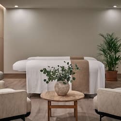 Relax in a serene space with a large bed, a round table, and comfortable armchairs.