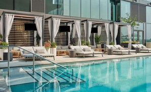 A modern outdoor pool area with lounge chairs, umbrellas, and potted plants. - Pendry Washington DC - The Wharf (Washington)