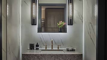 A modern bathroom with a marble sink, a mirror with black frames, and a vase with flowers.
