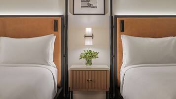 Habitación de hotel con dos camas, una mesita de noche con lámpara y un cuadro en la pared.