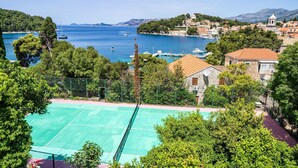 Un pueblo costero con cancha de tenis, barcos y montañas al fondo.