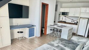 Un espacio habitable compacto con kitchenette, comedor y sofá.