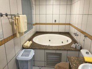 Un baño con bañera, toallero, cesto de ropa y retrete.