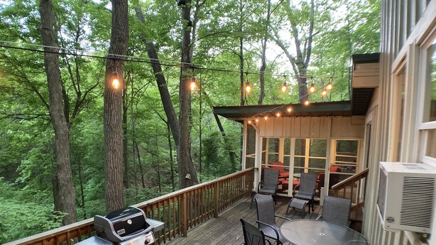 A deck with a grill, outdoor furniture, and string lights. - Treetops Cabin in the Woods! (Bloomingdale)