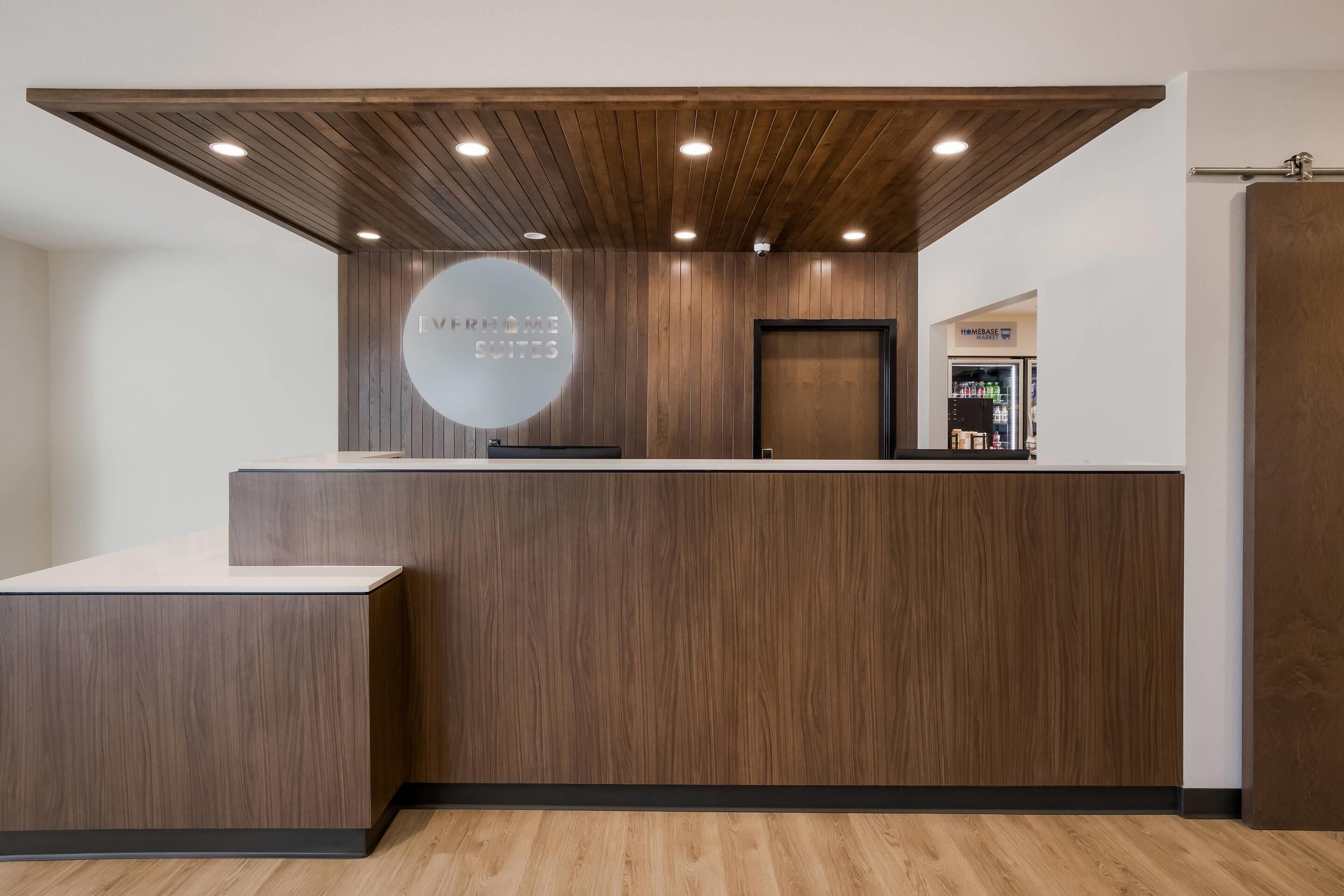 A reception desk with a wooden finish, a circular logo, and recessed lighting.
