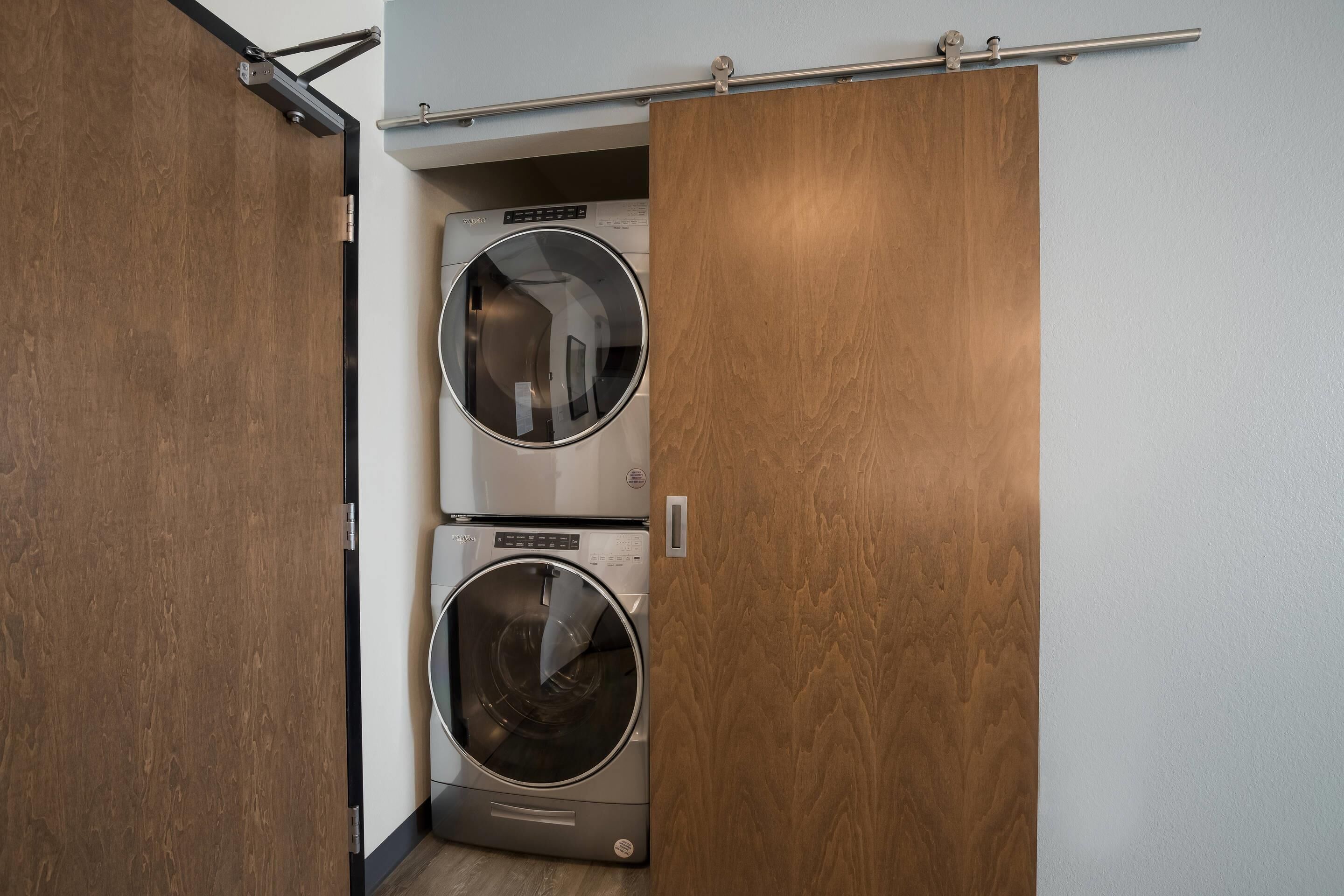 A compact laundry room with two stacked front-loading washing machines.
