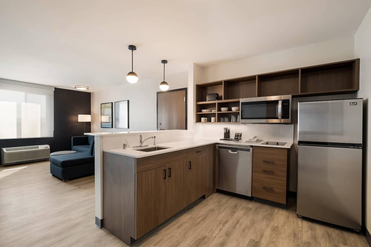 A modern kitchen with wooden cabinets, stainless steel appliances, and a built-in microwave.