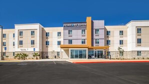 A hotel with a modern facade, a prominent entrance, and a clear blue sky. - Everhome Suites Corona (Corona)