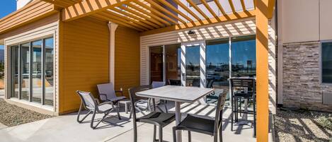 An outdoor patio with a pergola, seating, and a view of the cityscape.
