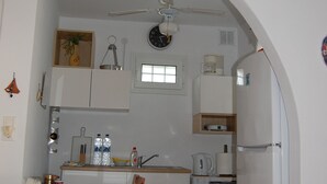 A compact kitchen with a dining table, chairs, a washing machine, and a refrigerator.