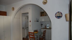 A compact kitchen with white cabinets, a dining table with two chairs, and a small island with a sink and countertop.