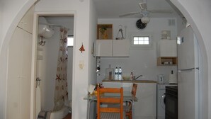 A compact kitchen with a dining area, a washing machine, and a ceiling fan.