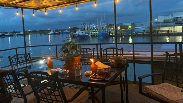 A dining area with a view of the marina at dusk. - Rougaroux Lodge @Venice Marina is a Sportsman dream! (Venice)