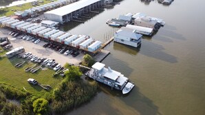 An aerial view of a marina with multiple docked boats, a large warehouse, and RVs parked on the shore. - Rougaroux Lodge @Venice Marina is a Sportsman dream! (Venice)