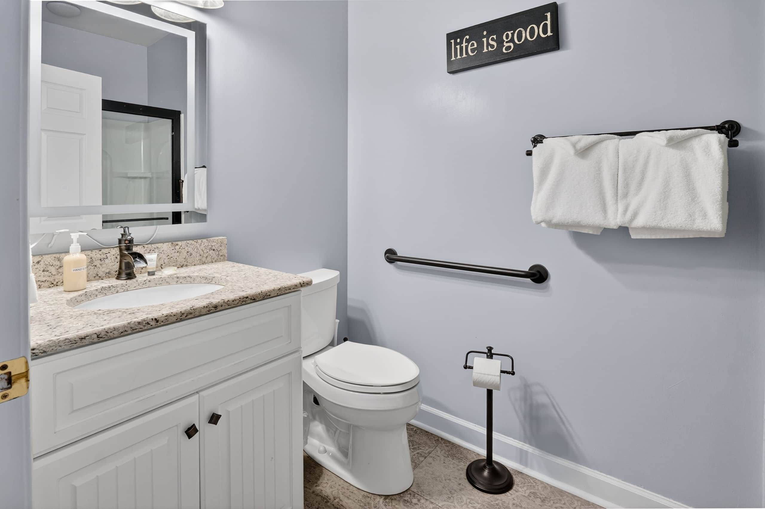 A bathroom with a white sink, mirror, toilet, and towel rack.