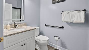 A bathroom with a white sink, mirror, toilet, and towel rack.