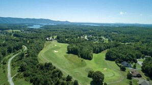 Eine Vogelperspektive auf einen Golfplatz mit einem See, bewaldeten Gebieten und Wohneinheiten.