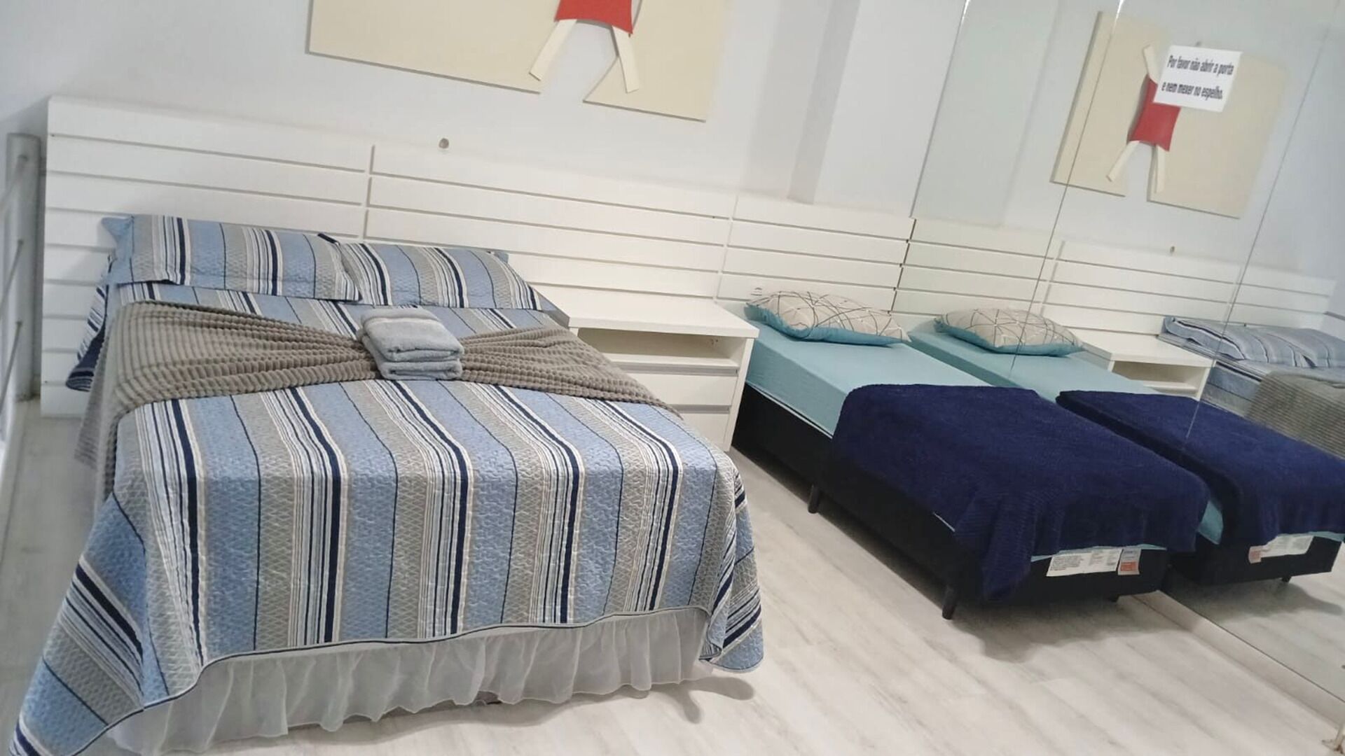 Un dormitorio con una cama grande, dos camas más pequeñas, un aparador blanco y un espejo.