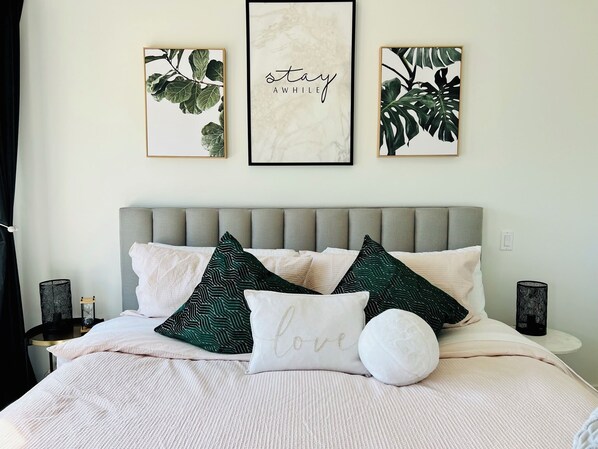 A neatly arranged bedroom with a bed, pillows, and three framed wall art pieces. - Peaceful Retreat with Breathtaking View (West Kelowna)