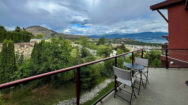A balcony with a view of a mountainous landscape, a small table, and two chairs. - Peaceful Retreat with Breathtaking View (West Kelowna)