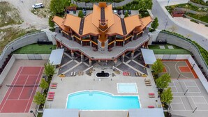 A modern building with a central pool, tennis courts, and a covered seating area. - Peaceful Retreat with Breathtaking View (West Kelowna)