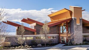 A modern building with a stone facade, large windows, and a sloped roof. - Peaceful Retreat with Breathtaking View (West Kelowna)