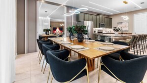 A modern dining area with a long wooden table set for six, surrounded by dark chairs. - 6BR house sleeps 16 with private pool (Kissimmee)