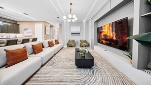 A modern living room with a large flat-screen TV, a black coffee table, and a patterned rug. - 6BR house sleeps 16 with private pool (Kissimmee)