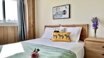 A neatly made bed with a green bedspread, a single rose decoration, and a zebra-themed pillow.